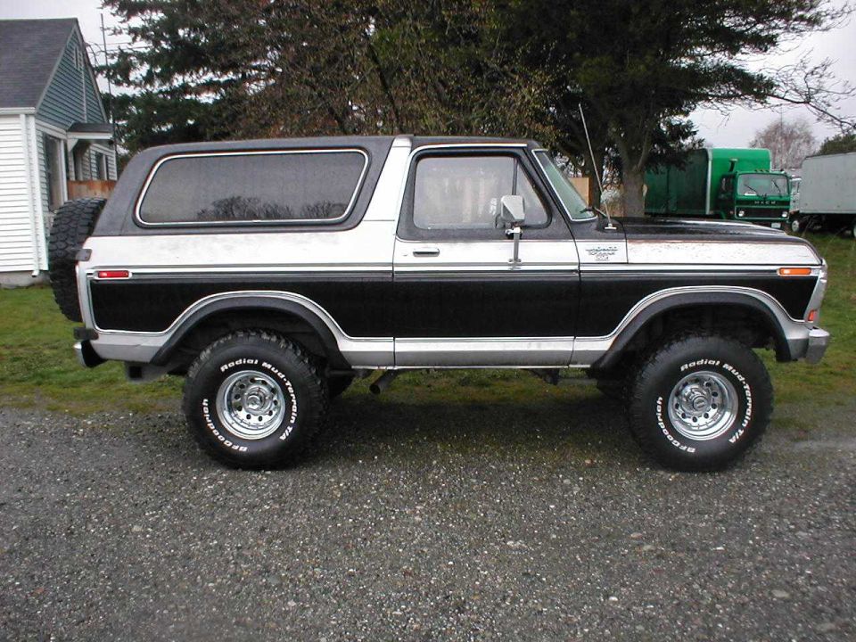 Black and silver 1979 Ford Bronco SUV, driver-side profile on gravel lot
