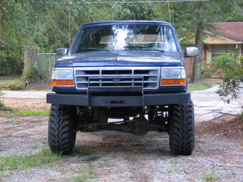 1995 Ford Bronco - This lifted blue Ford Bronco features a custom front bumper and oversized tires.
