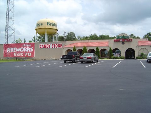 1986 Ford Bronco - A view of a parking lot outside of Bridges Boat Outlet and Candy Store, with a water tower visible.