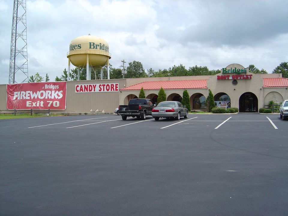 Parking lot in front of Bridges Boat Outlet and Candy Store, with a water tower in the background