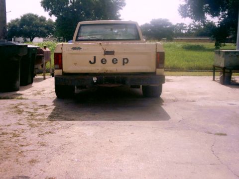 1980 Ford Bronco - Rear view of a cream-colored Jeep pickup truck, identified by its tailgate lettering.