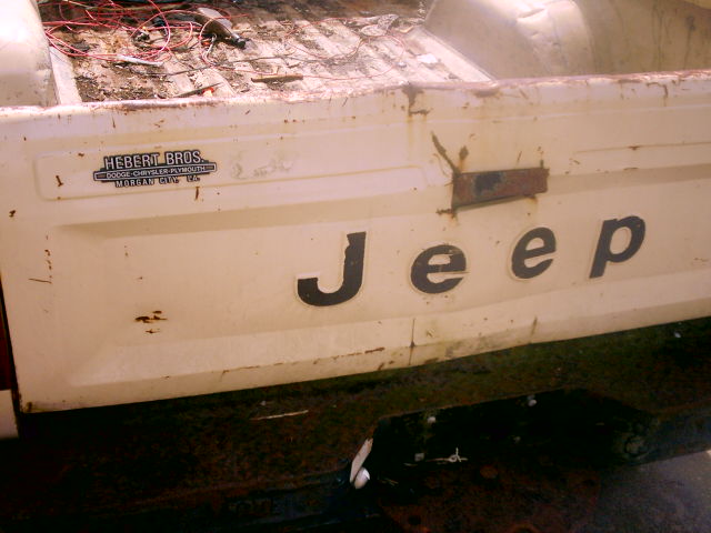 White Jeep pickup truck tailgate with 'Jeep' lettering and 'Hebert Bros.' dealer sticker