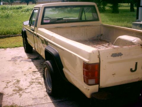 1980 Ford Bronco - This Jeep Comanche pickup truck is seen from the rear 3/4 angle.