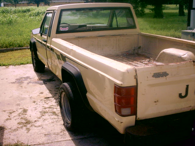 Cream-colored Jeep Comanche pickup truck, rear 3/4 view, showing bed and tailgate
