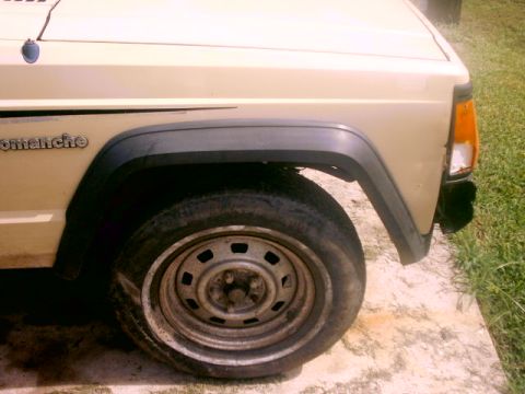 1980 Ford Bronco - The 'Comanche' badge is visible on the side of this beige vehicle's front fender.