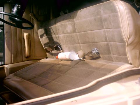 1980 Ford Bronco - The interior of the vehicle shows a worn bench seat with a seatbelt and a can of something on it.
