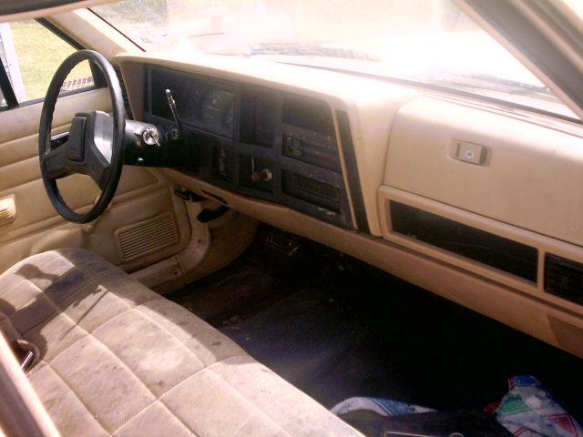Tan interior of a car with a quilted seat, dashboard, and steering wheel. The "SUPERMOTORS" logo is visible