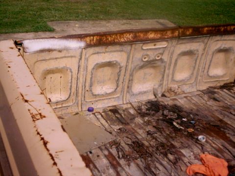 1980 Ford Bronco - The interior of a weathered truck bed shows signs of rust and wear on its ribbed floor and side panels.