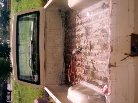 1980 Ford Bronco - Pickup truck bed interior with wiring and debris. The cab and window are visible.