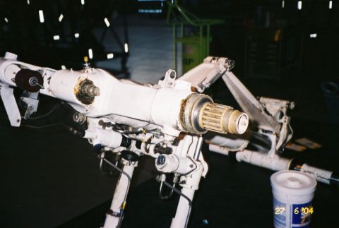 1988 Ford Bronco - Close-up of a complex mechanical assembly, possibly aircraft landing gear, with visible hydraulic lines and a splined shaft.