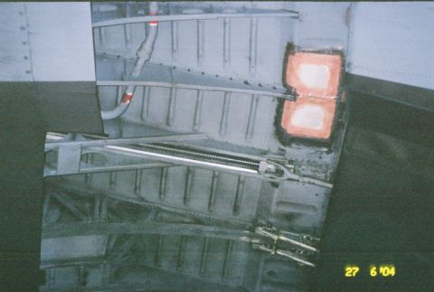 1988 Ford Bronco - The underside of a vehicle shows structural components and some repair work on the metal.