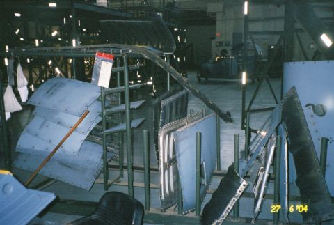 1988 Ford Bronco - Metal body panels are organized on racks, likely awaiting assembly or repair.