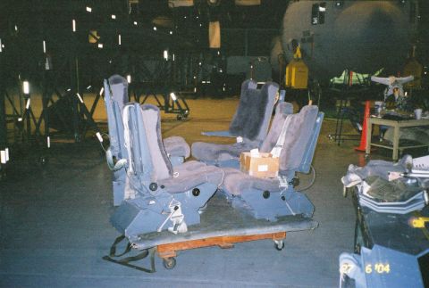 1988 Ford Bronco - Multiple rows of airline seats are staged on a cart, with a large aircraft in the background.