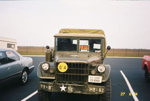1988 Ford Bronco - A vintage US Army truck is parked in a lot, displaying a 'FOR SALE' sign in its windshield.