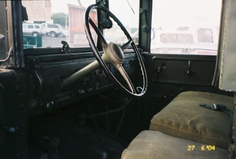 1988 Ford Bronco - The interior of a truck shows a steering wheel and seat, with other vehicles visible outside.