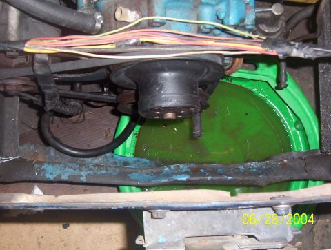 1974 Ford Mustang II - Close-up of a car's water pump and leaking coolant collected in a green pan.