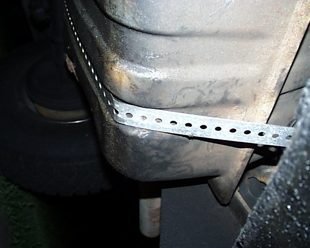 Underside of a vehicle with a metal strap attached to the frame
