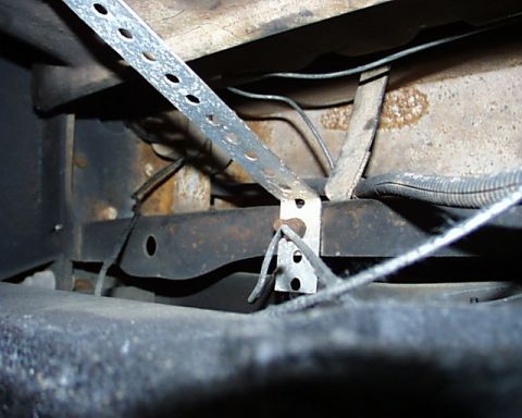 1988 Ford C-350 (Centurion Conversions) - Close-up of vehicle undercarriage with visible metal strapping and wiring.