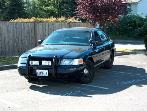 2001 Ford Crown Victoria - A dark blue 2001 Ford Crown Victoria police car is parked in a lot, showing its front three-quarter view.