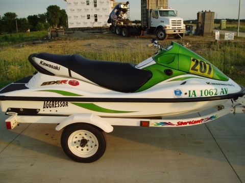 1987 Ford Bronco - Kawasaki STX-R Aggressor jet ski with number 207 on the front, on a trailer at a construction site.