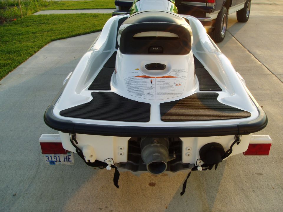 Rear view of a white jet ski on a trailer, with a pickup truck behind it
