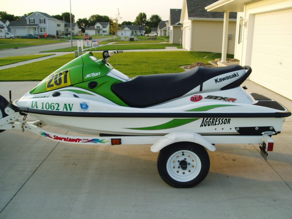 White and green Jet Ski on a trailer, with 'Kawasaki' and 'Aggressor' visible