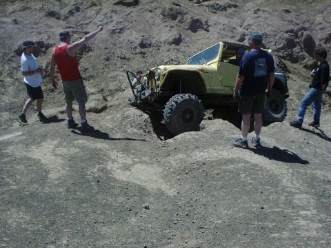 1978 Ford Bronco - A yellow Jeep Wrangler tackles a challenging off-road course with onlookers observing the action.