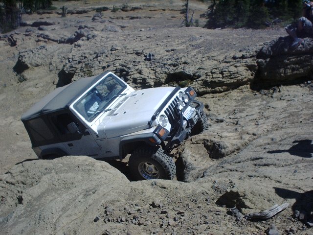 White Jeep Wrangler navigating a rocky off-road trail