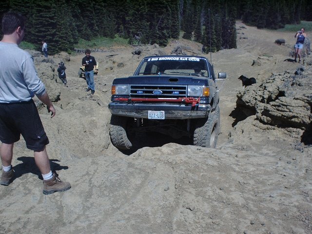 Ford Bronco navigating rocky terrain, with people watching