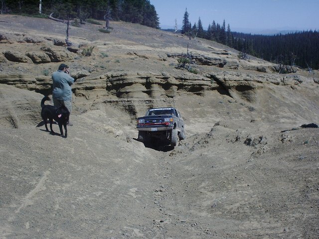 Dark blue pickup truck navigating a steep, rocky incline