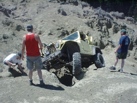 1978 Ford Bronco - A yellow Jeep Wrangler navigates a challenging rocky off-road course with onlookers present.