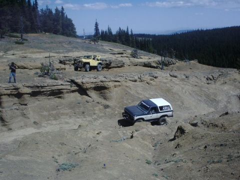 1978 Ford Bronco - Two off-road vehicles navigate a challenging rocky landscape under a clear blue sky.