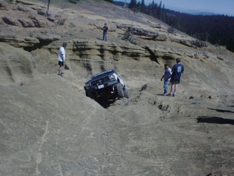 1978 Ford Bronco - A white SUV navigates a challenging off-road course on a steep, rocky hill.