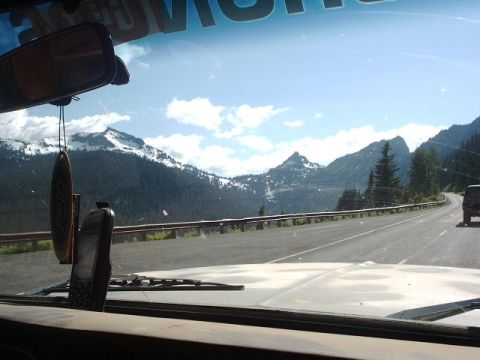 1978 Ford Bronco - View from inside a vehicle driving on a scenic mountain road with snow-capped peaks.