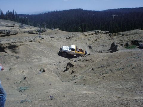 1978 Ford Bronco - A 1978 Ford Bronco navigates a steep, rocky off-road terrain under a clear blue sky.