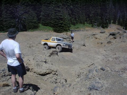 1978 Ford Bronco - A 1978 Ford Bronco tackles a challenging off-road course with a person watching.