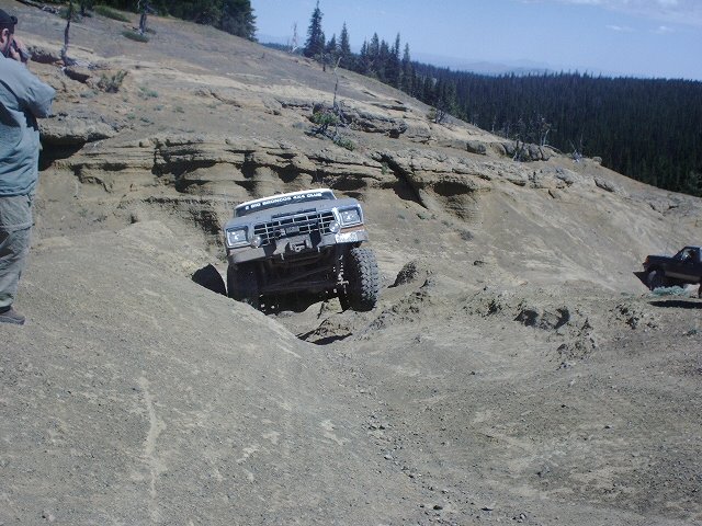 Off-roader climbing steep dirt hill, another truck in background