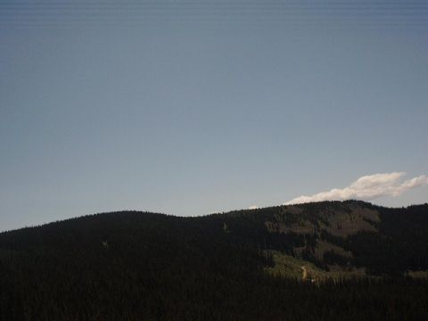1978 Ford Bronco - A scenic view of a mountain range with a dirt road visible on the slope, under a vast expanse of blue sky.