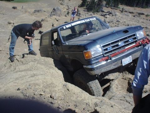 1978 Ford Bronco - A Ford Bronco is stuck in a dirt ditch, with a person filming the situation and another person assisting.