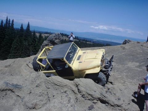 1978 Ford Bronco - A yellow off-road vehicle is being driven over large rocks on a mountain trail.