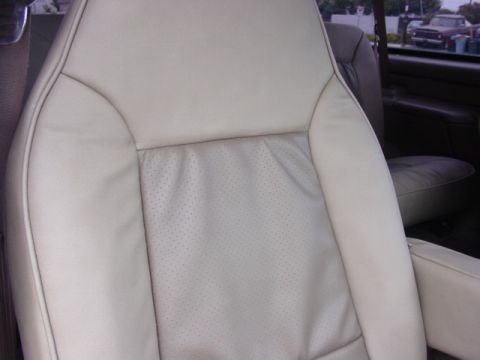 1992 Ford Bronco - The interior of a vehicle shows a close-up view of a perforated leather seat with stitching details.