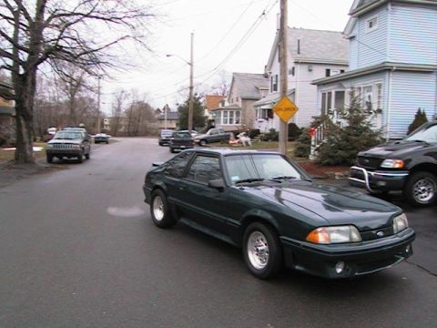 2000 Jeep Liberty - A dark green coupe is parked on a street with houses and other vehicles visible.