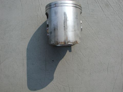 1985 Ford Bronco - A single piston is shown against a textured gray background, casting a distinct shadow.