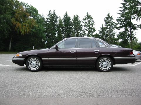 1992 Ford Crown Victoria - A side profile of a dark purple Ford Crown Victoria sedan is shown parked in an outdoor lot.