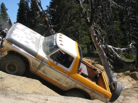 1995 Ford Bronco - Pickup truck attempts to climb a challenging rocky trail in a wooded area.