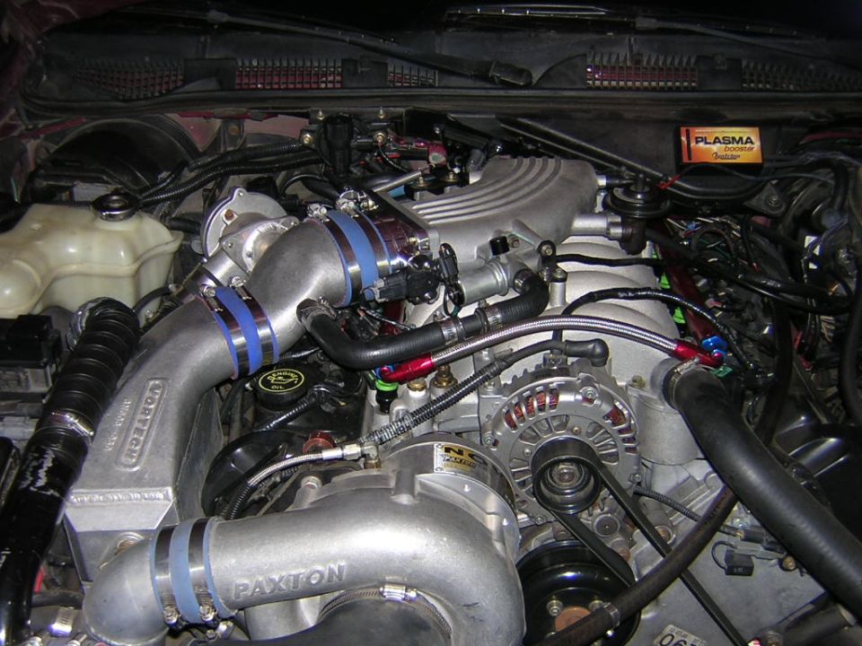 Engine bay with twin turbochargers, intercooler piping, and various hoses. Paxton and Vortech branding visible