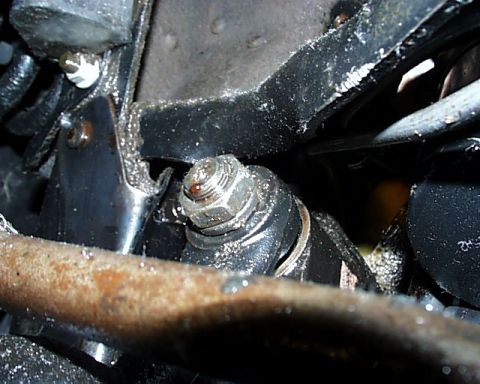 1988 Ford C-350 (Centurion Conversions) - Close-up view of a rusty metal bar and a bolted bracket, likely part of a vehicle's undercarriage.