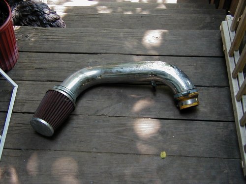 Polished aluminum cold air intake tube with red cone filter on a wood deck