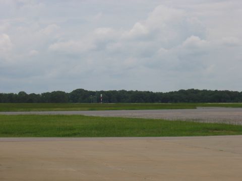 1988 Ford Bronco - An airport runway stretches out with a line of trees in the distance under a cloudy sky.