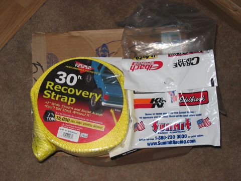 1988 Ford Bronco - Various automotive performance parts and a recovery strap are laid out on the floor.